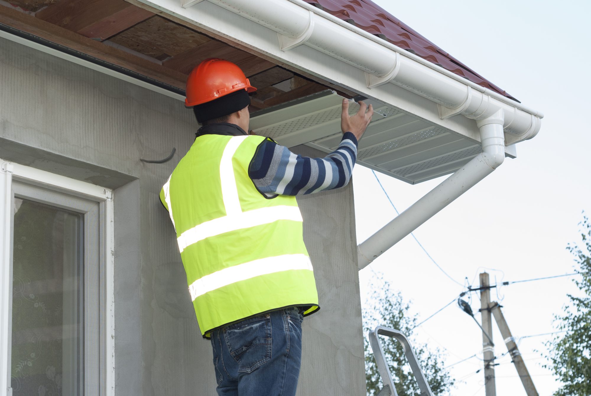 Construction worker mounts a soffit on the roof eaves